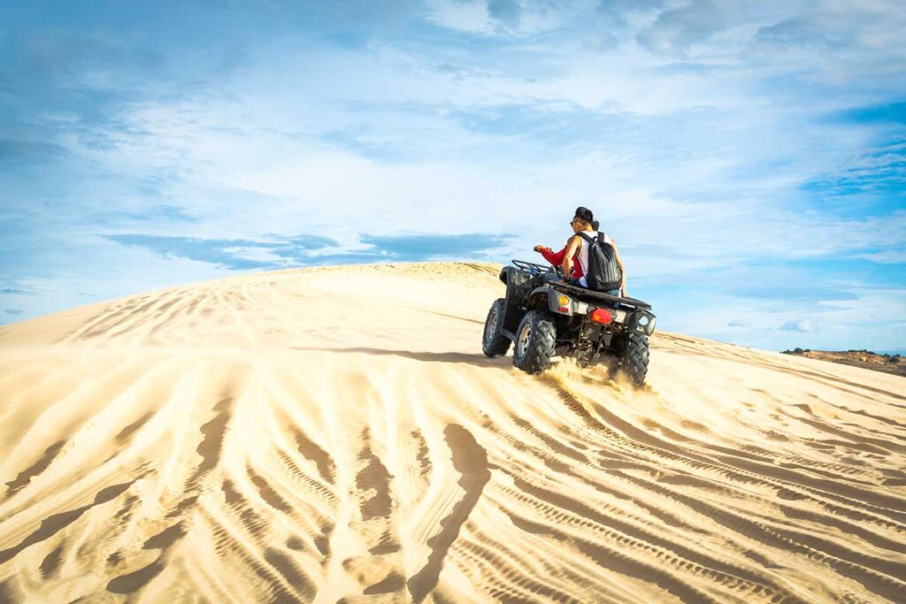 Two guys sitting on an ATV driving over the white sand dunes in Mui Ne.