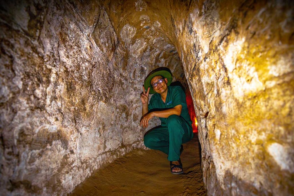 A local tour guide kneeling down inside the Cu Chi Tunnels, one of the best things to do in Vietnam.