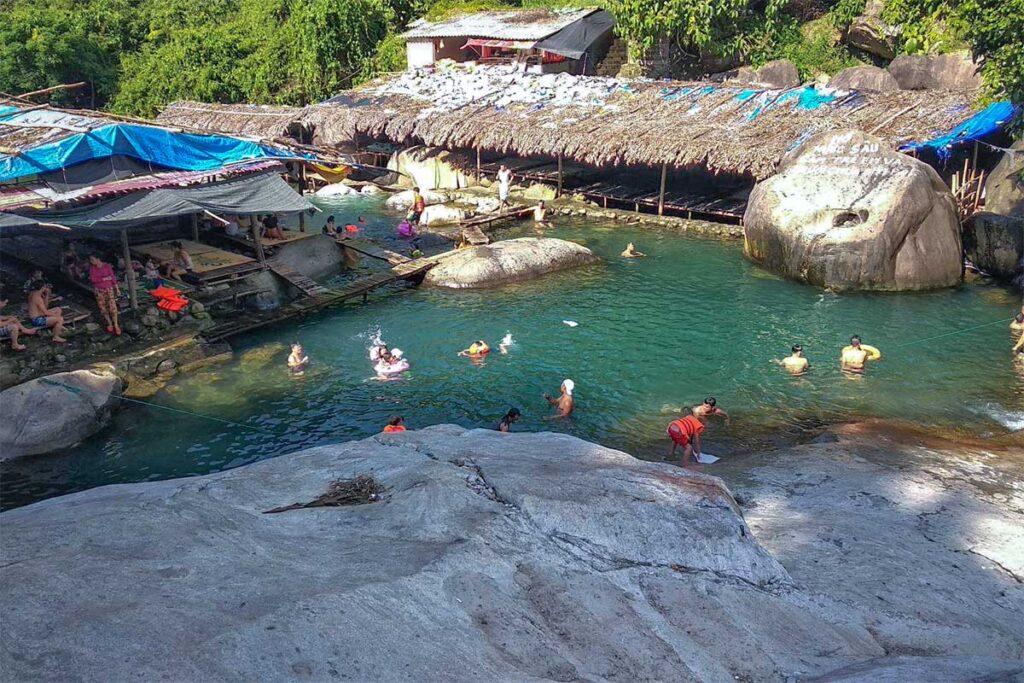 Many locals are swimming in a natural pool surrounded by small huts part of the Elephant Springs (Suoi Voi)