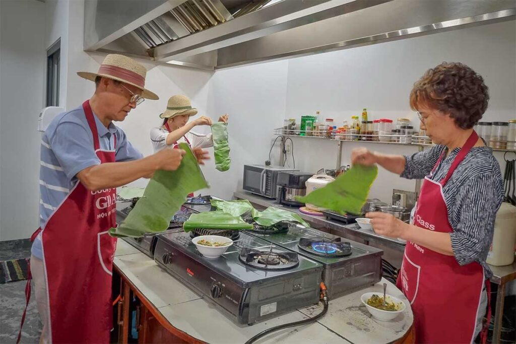 Participants wrapping food in banana leaves at Gioan Cookery School Hoi An