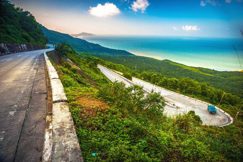 A view of the Hai Van Pass road winding down with beaches in the distance.
