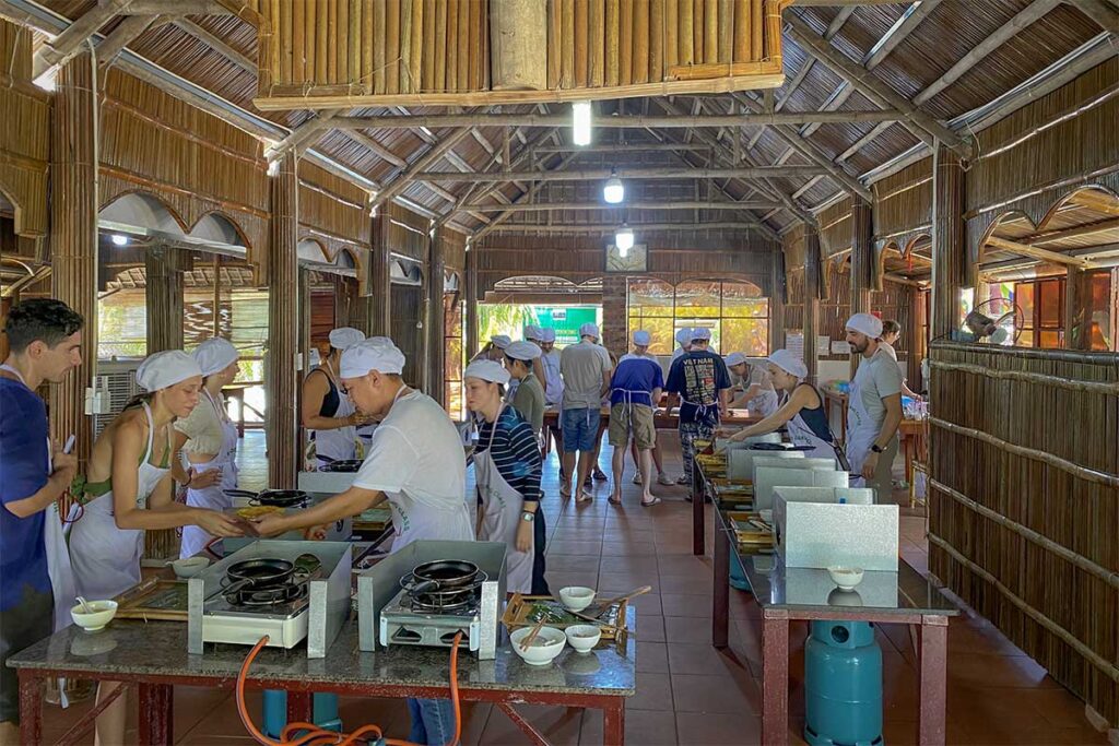 Tourists learning to cook traditional Vietnamese dishes during a Hoi An cooking class