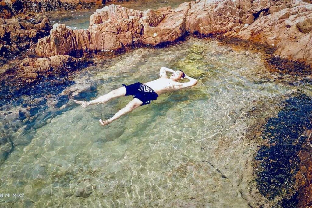 Traveler floating in a natural rock pool on Hon Ngang Island, a hidden snorkeling and swimming spot near Bai Xep, Quy Nhon.