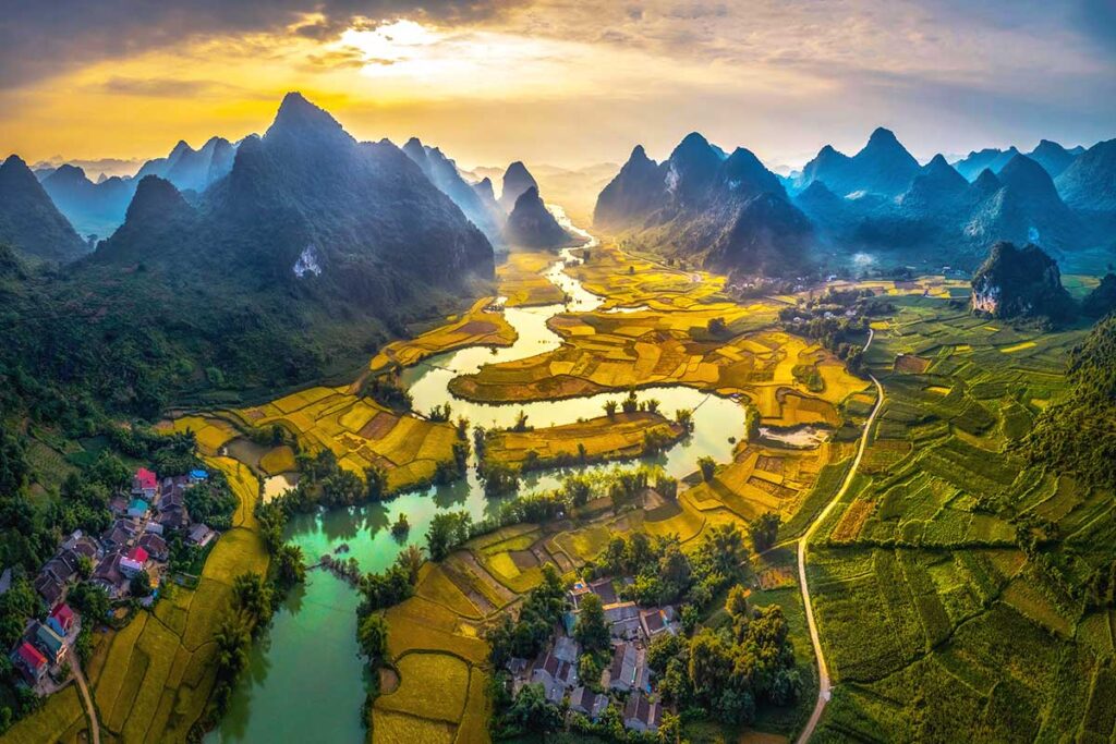 Aerial view of Phong Nam Valley with a river running through a valley surrounded by rice fields and mountains.