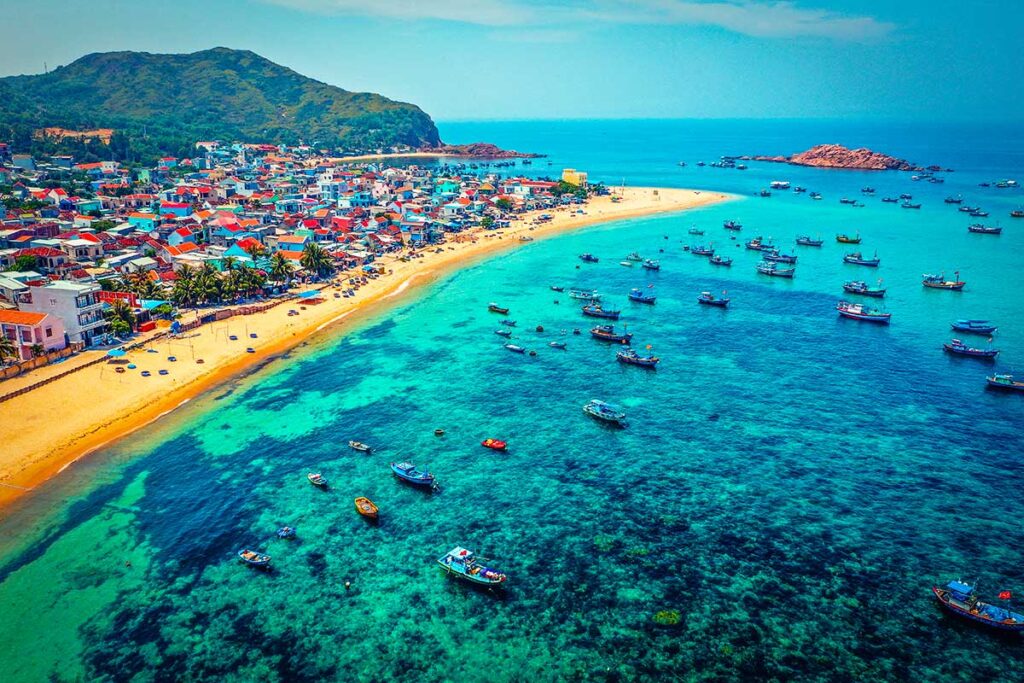 Aerial view of a local fishing village near Quy Nhon, showing the beach, village, and fishing boats in the water.