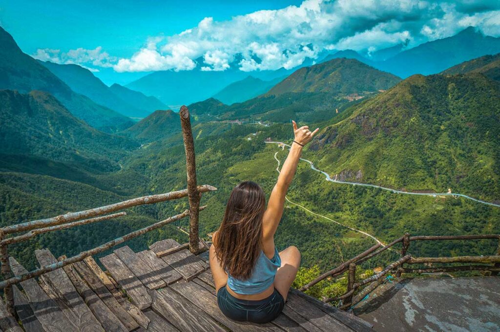 A girl sitting on a wooden platform serving as viewpoint over Tram Ton pass