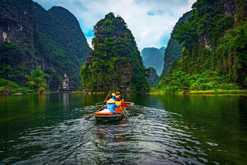 a rowing boat going over the river between high karst mountains in Trang An, Ninh Binh