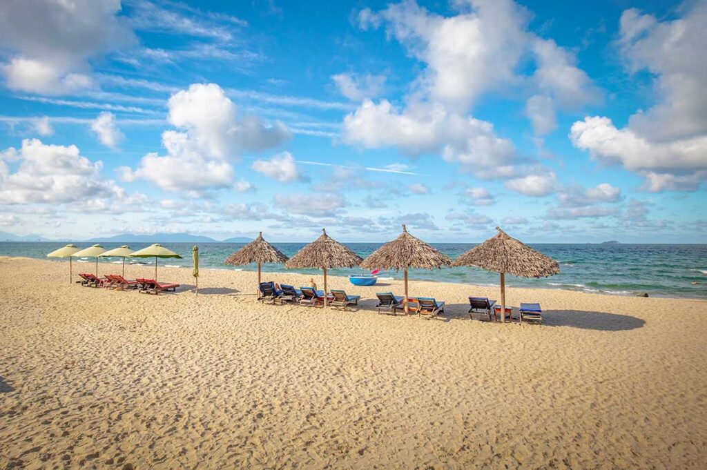 Scenic stretch of An Bang Beach with rows of umbrellas and sunbeds facing the sea in Hoi An