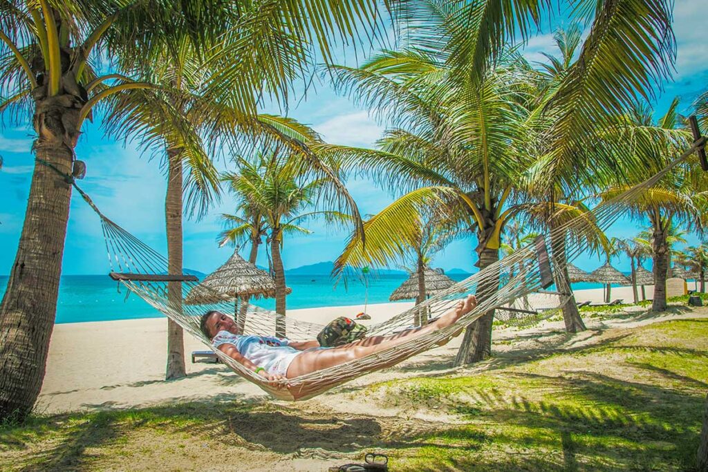 Woman relaxing in a hammock under palm trees on An Bang Beach in Hoi An, Vietnam