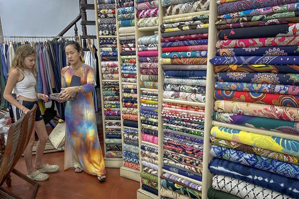 Customer choosing fabrics at Bebe Tailor in Hoi An, one of the best tailors in town known for high-quality custom made clothing.