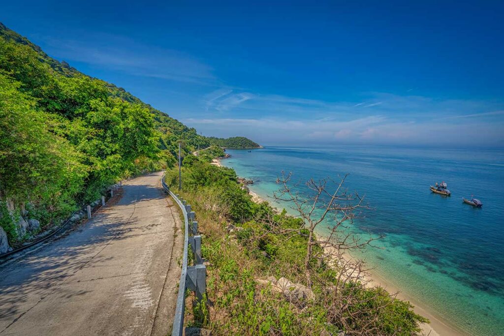 Curving coastal road on Cham Island’s east side, overlooking cliffs and blue sea — one of the most scenic drives on the island.