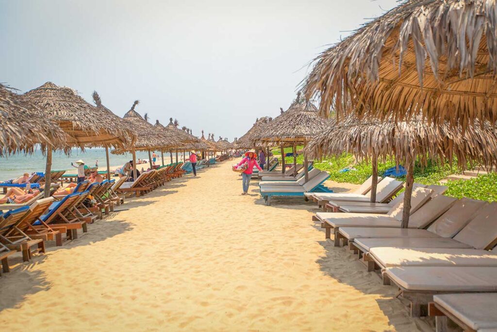 Rows of sun loungers and thatched umbrellas along the sandy shore of Cua Dai Beach in Hoi An