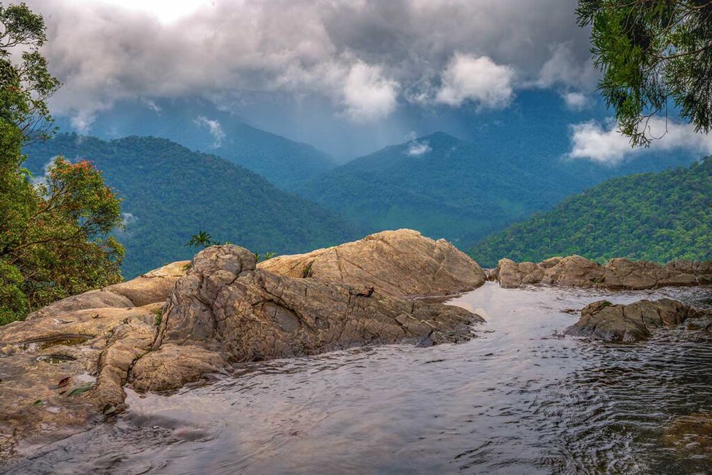 Do Quyen Waterfall seen from the top of the falls and the view over the mountains in the background of Bach Ma National Park