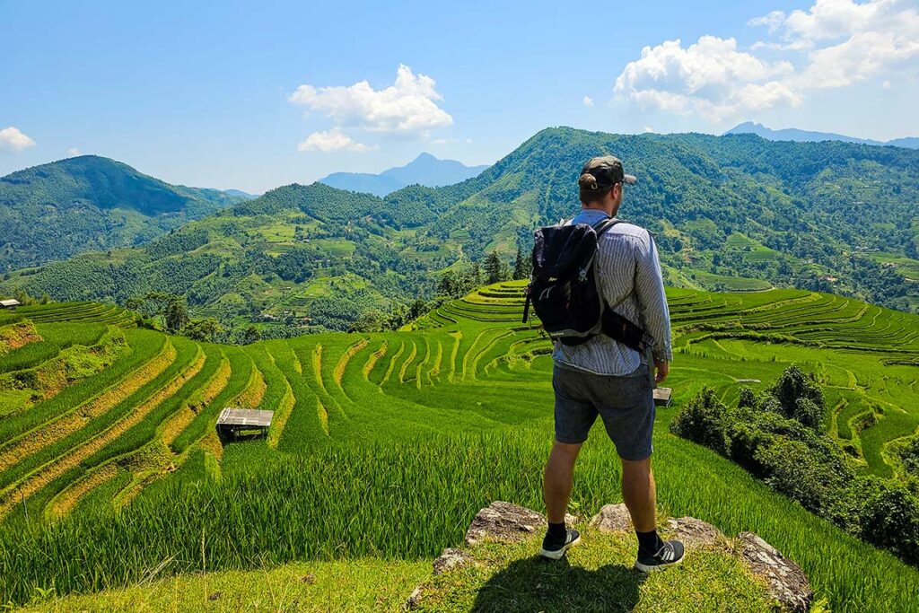A tourist is enjoying the view over terraced rice fields during a trekking in Hoang Su Phi