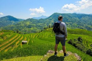 A tourist is enjoying the view over terraced rice fields during a trekking in Hoang Su Phi