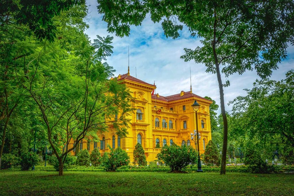 The yellow Presidential Palace with garden seen from the grounds of Ho Chi Minh Stilt House