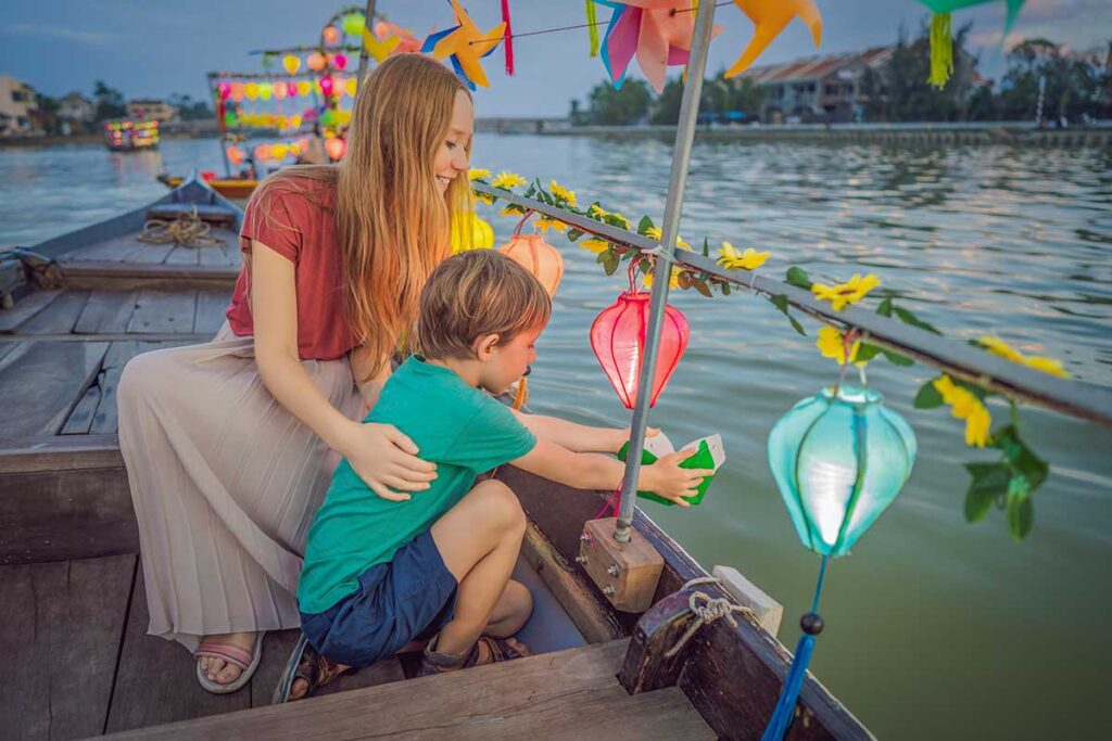 Hoi An with kids – mother and child releasing lanterns on a boat ride along the Thu Bon River at sunset