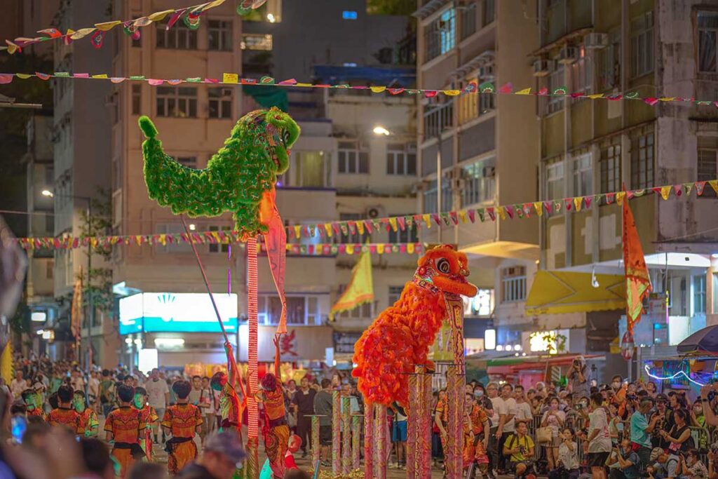 Lion dance in the evening with large crowd watching in the street during Mid Autumn Festival in Hanoi