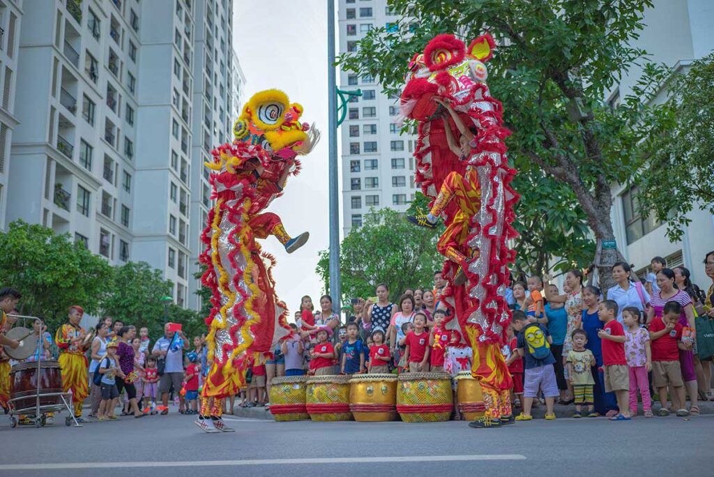 A lion dance right on the street with people watching during Mid Autumn Festival in Hanoi