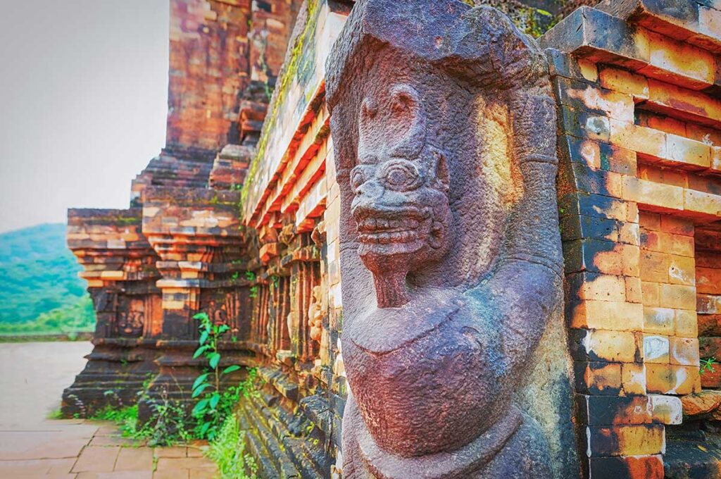 Sandstone guardian carving on a Cham temple corner at My Son Sanctuary, showing crisp brick courses and sculpted detail