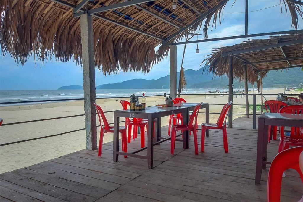 A local seafood restaurant build on stilts at Lang Co Beach with plastic chairs and simple setup and ocean views
