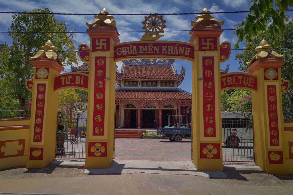 Entrance gate of Dien Khanh Pagoda on Tam Hai Island, with red and yellow Buddhist decorations and traditional Vietnamese architecture.