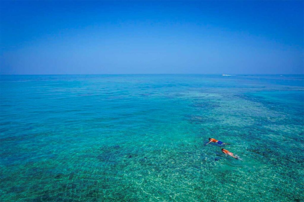 Travelers snorkeling in the clear blue waters around Tam Hai Island, exploring shallow coral reefs near the small offshore islets.
