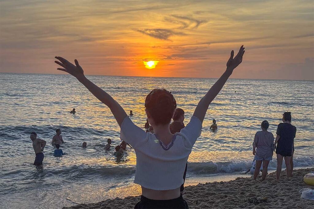 A local girl from Hue holding her hands up during the sunset at Thuan An Beach