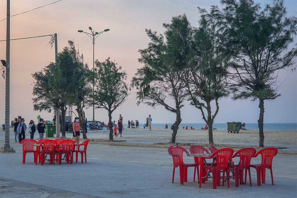 Plastic chairs and locals on the parking area in front of Thuan An Beach in Hue