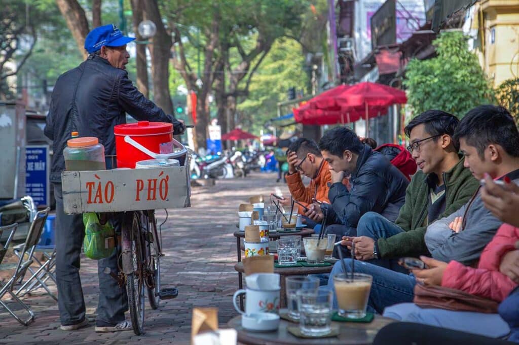 Locals sitting on the street at a street stall selling Vietnamese coffee in Hanoi