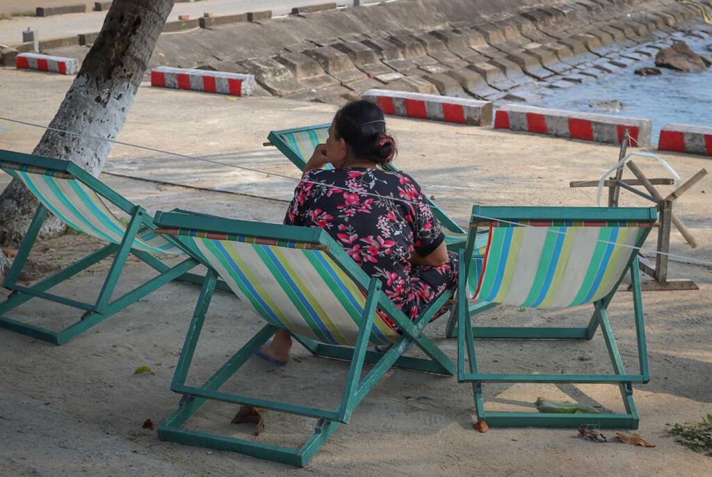 Local woman relaxing on deck chairs by the seaside in Bai Lang village, Cham Island, enjoying a quiet afternoon view.