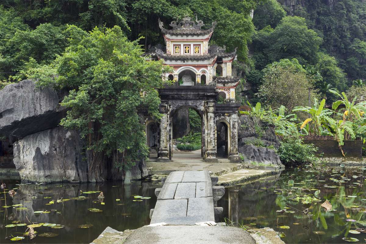 Premium Photo  Lone tourist with traditional vietnamese hat at bich dong  pagoda entrance gate, ninh binh vietnam, buddhist temple set amid jungle  and karst mountain range. traveling alone, keep social distancing.