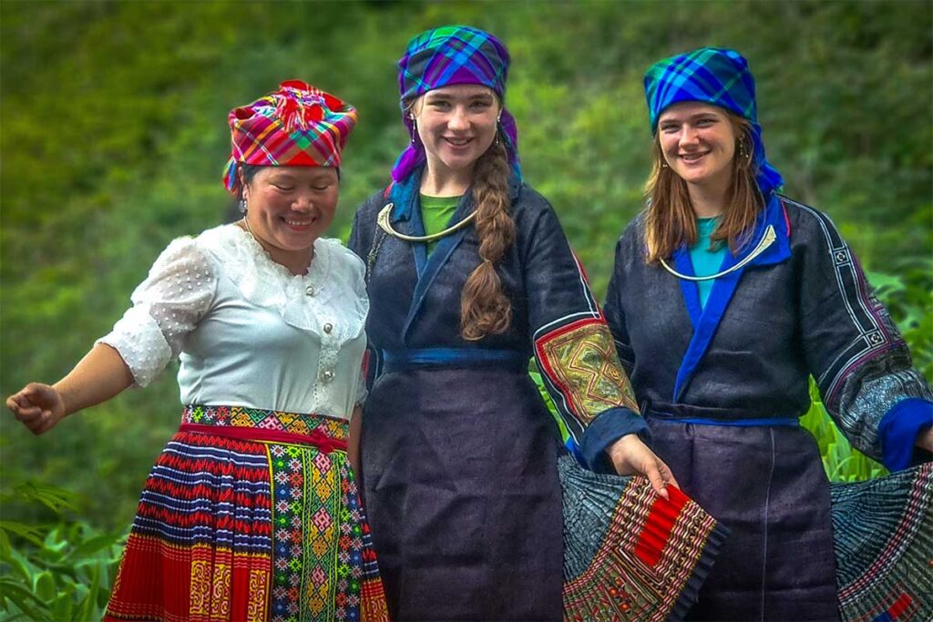 Two foreign girls standing dressed with ethnic costume together with a local ethnic minority woman