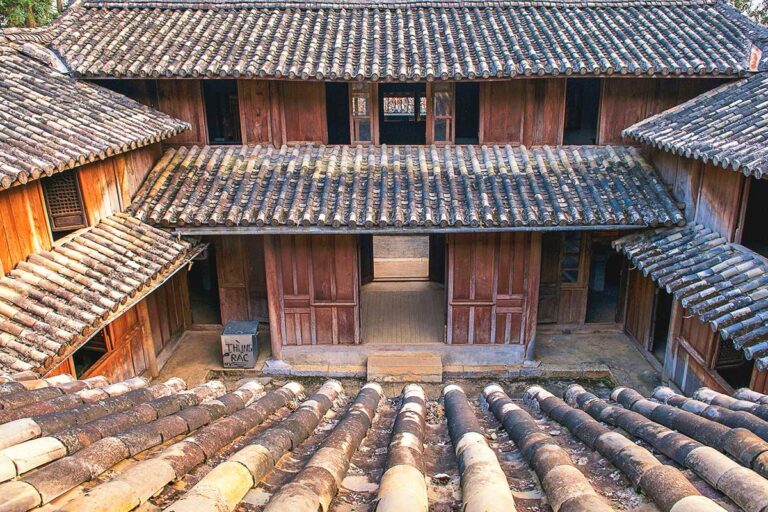 View from the second floor of the Hmong King Palace, looking down into one of the inner courtyards with wooden walls and traditional tiled roofs.