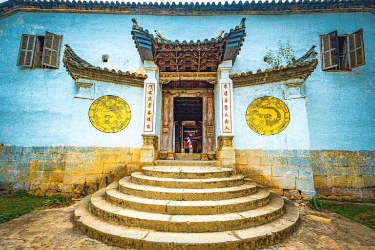 Entrance gate of the Hmong King Palace, featuring a sturdy stone wall with white and yellow circular symbols on both sides.