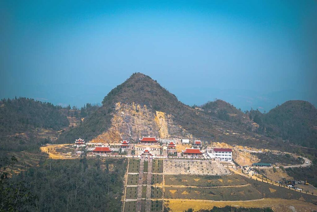 Lung Cu Pagoda complex under construction – A massive temple complex on the mountaintop near the Lung Cu Flag Tower, with long staircases leading up to the nearly finished pagoda.