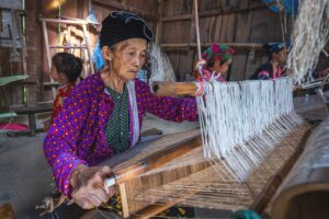 An elderly ethnic woman weaving fabric using traditional methods in Lung Tam Village, Ha Giang.