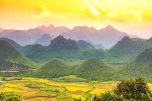 A breathtaking sunset over the Twin Mountains in Quan Ba, Ha Giang, casting a golden glow across the sky.