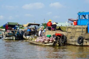 Vendors selling produce such as onions and cassava directly from boats at Cai Rang Floating Market in Can Tho.