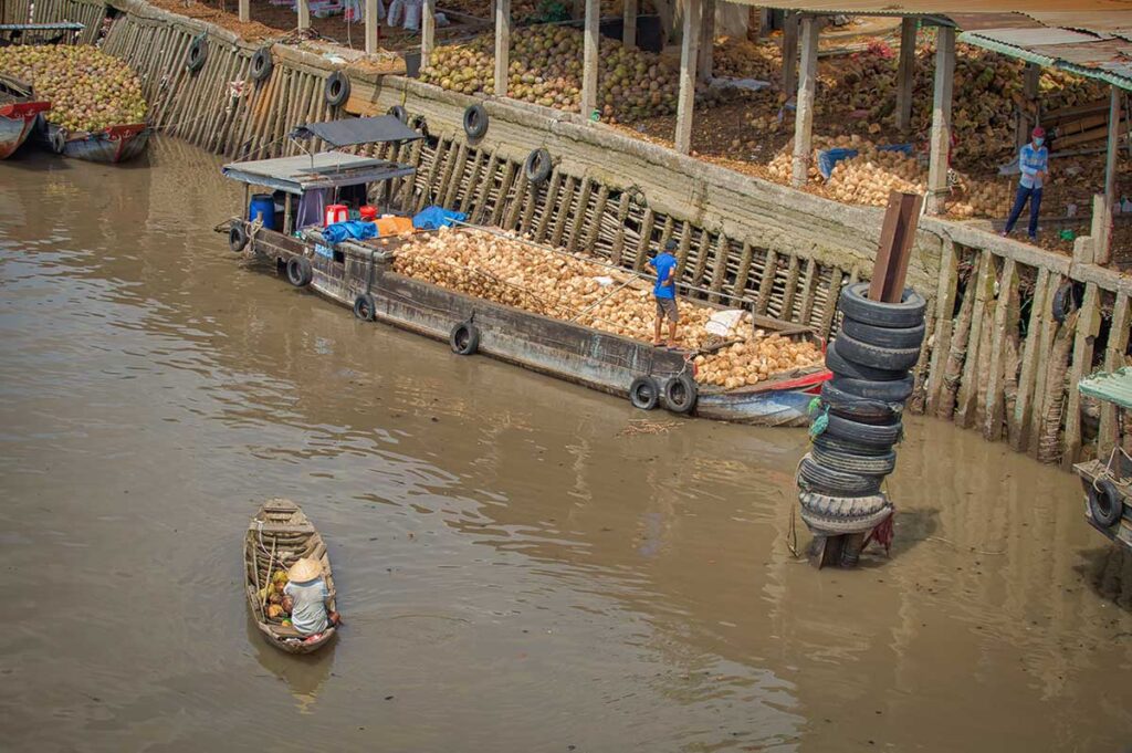 Coconut boats and traders on the river in Ben Tre, Vietnam, highlighting the province’s role as the coconut capital of the Mekong Delta.