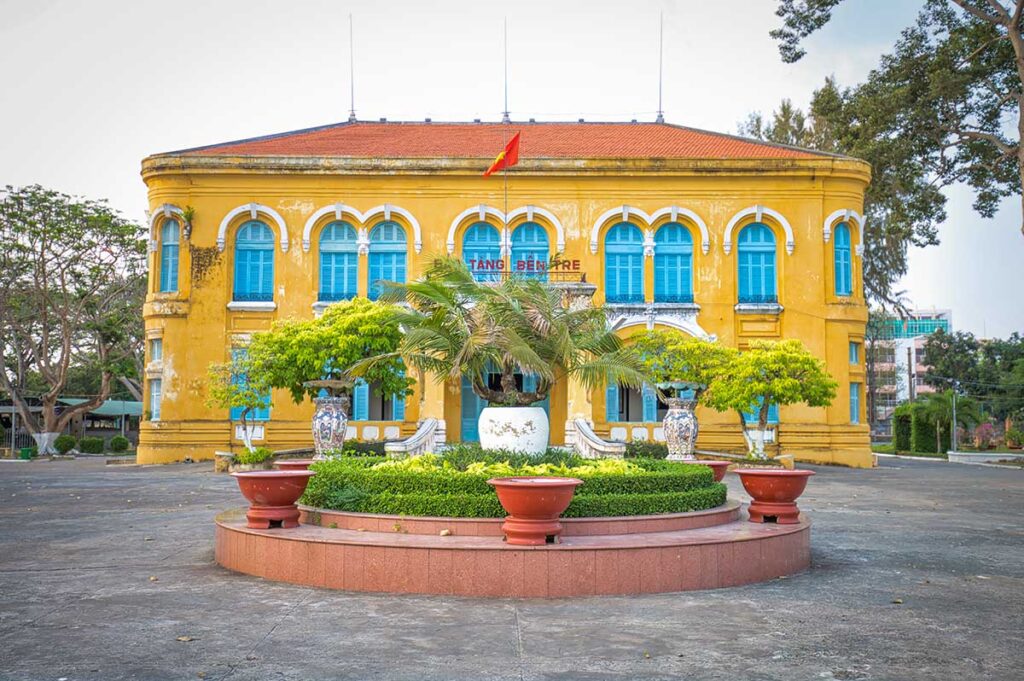 Exterior of the Ben Tre Museum in Vietnam, a colonial yellow building with blue shutters showcasing the province’s history and culture.
