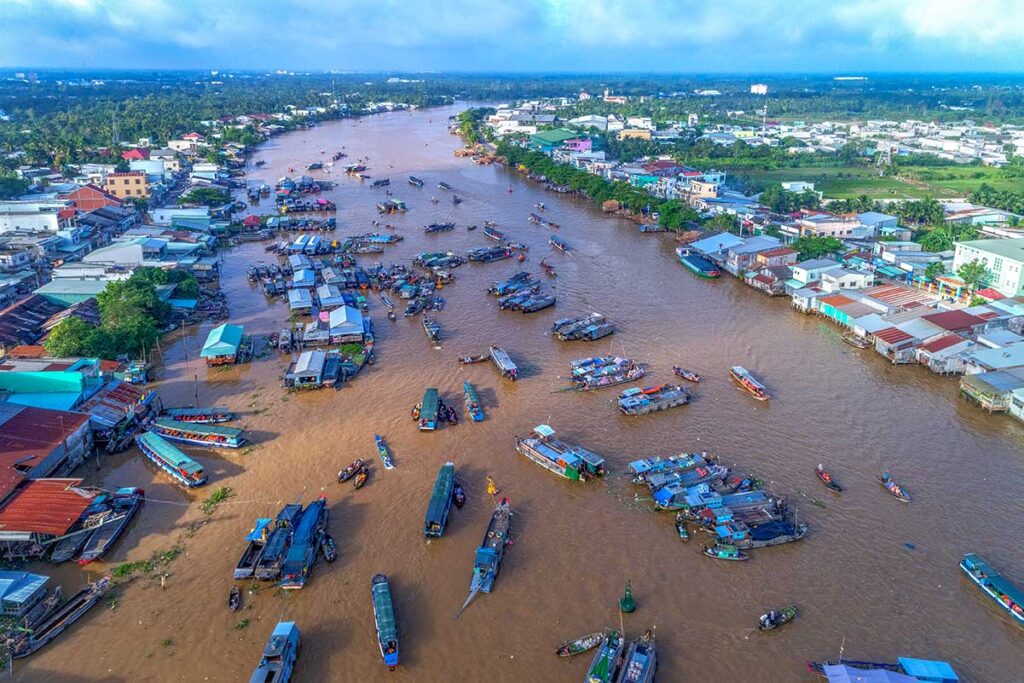 Aerial view of Cai Rang Floating Market on the Hau River, showing dozens of trading boats clustered together near Can Tho city.