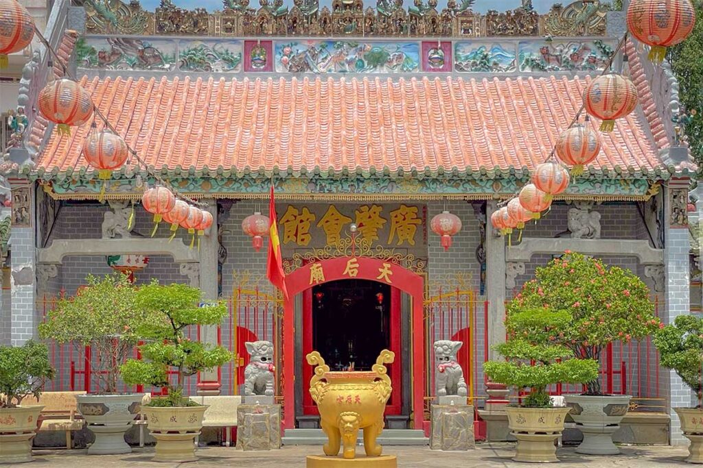Cantonese Tin Hau Temple in Vinh Long, a colorful Chinese-style pagoda with red lanterns, guardian statues, and intricate rooftop carvings.