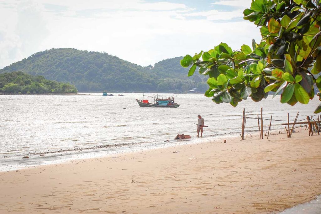 Quiet Bai No Beach in Ha Tien with fishing boat and local fisherman on the shore.