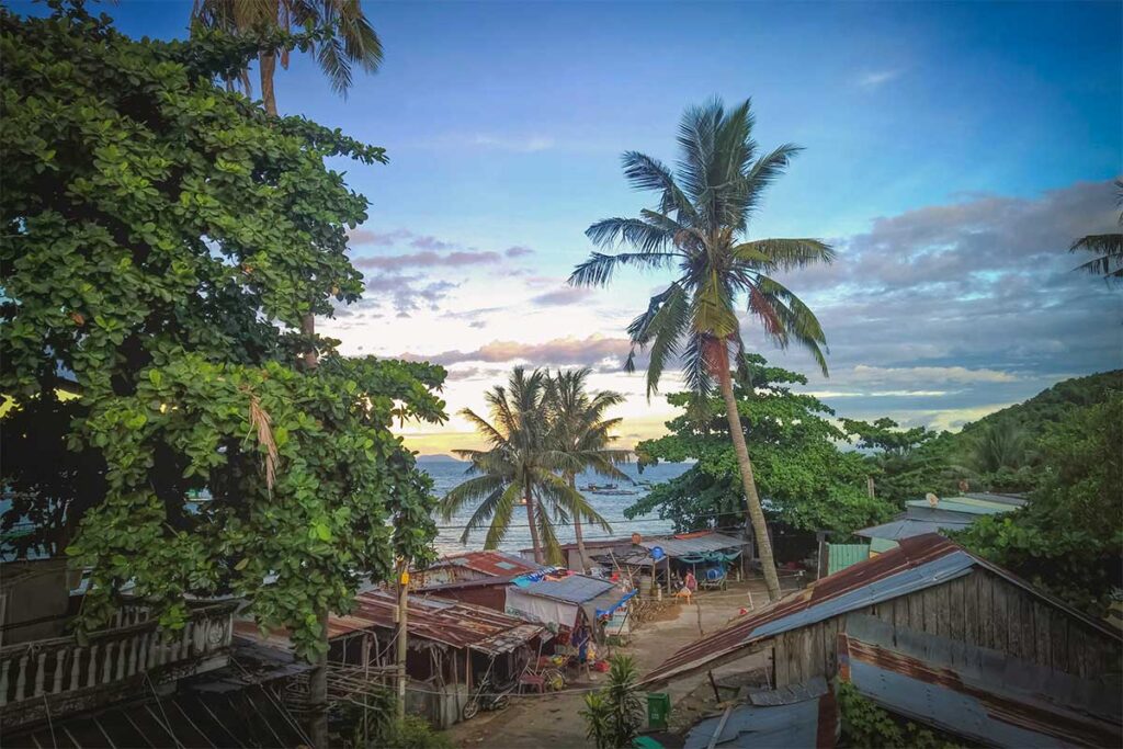 Fishing village view on Hai Tac Island, part of the Ha Tien Islands, with palm trees and sea backdrop.