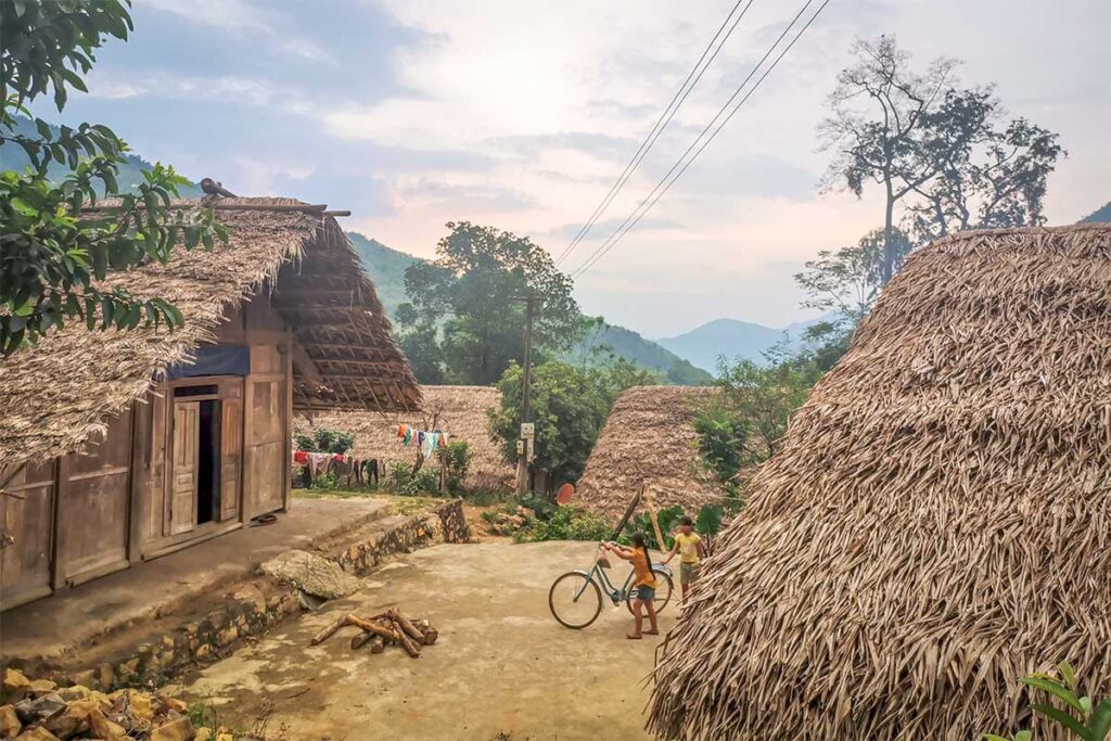 Traditional stilt houses uses as local homestays with palm leaves and dirt roads in a very rural setting nearby  Hoa Binh Lake