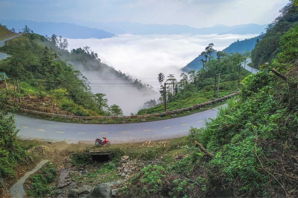 A road part of the Khau Pha Pass in Mu Cang Chai with motorbike parked and forest and mountain views on the background