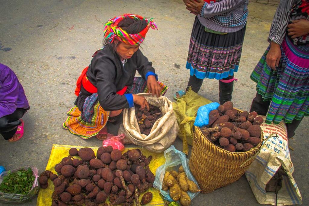 An ethnic woman selling local produce on the floor in front of the Lai Chau Central Market