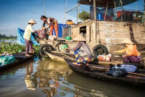 Women preparing food on boats at Long Xuyen Floating Market in An Giang, Vietnam