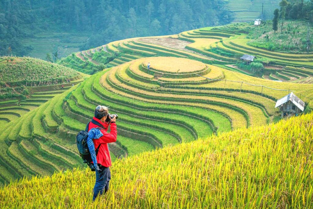 A photographer making photos during a trekking through the terraced rice fields of Mu Cang Chai